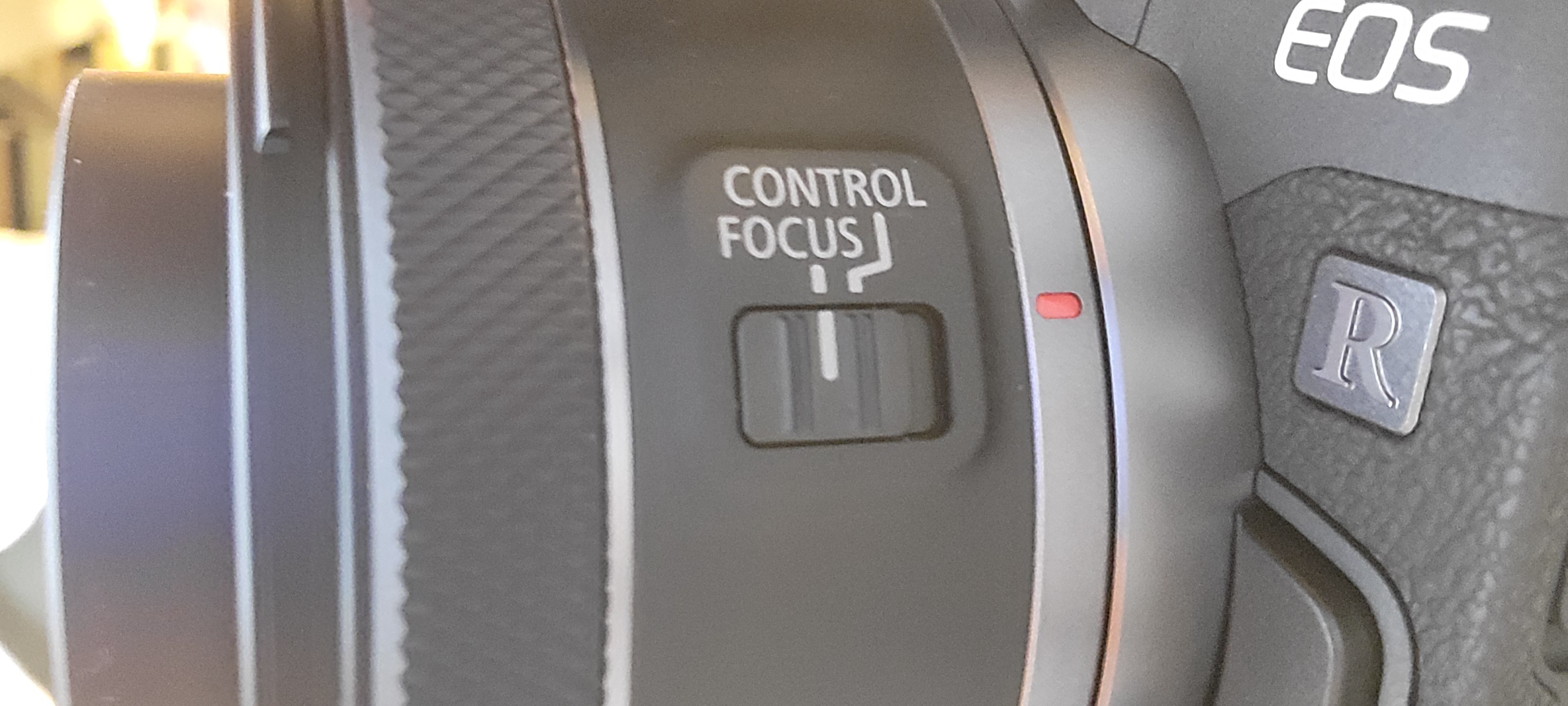 photo of the side of a SLR camera lens with a slider switch set so the line aligns with the line under the word 'FOCUS'